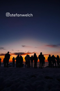 A group of people standing on top of a snow covered slope. (No keywords related to stargazing were provided.)