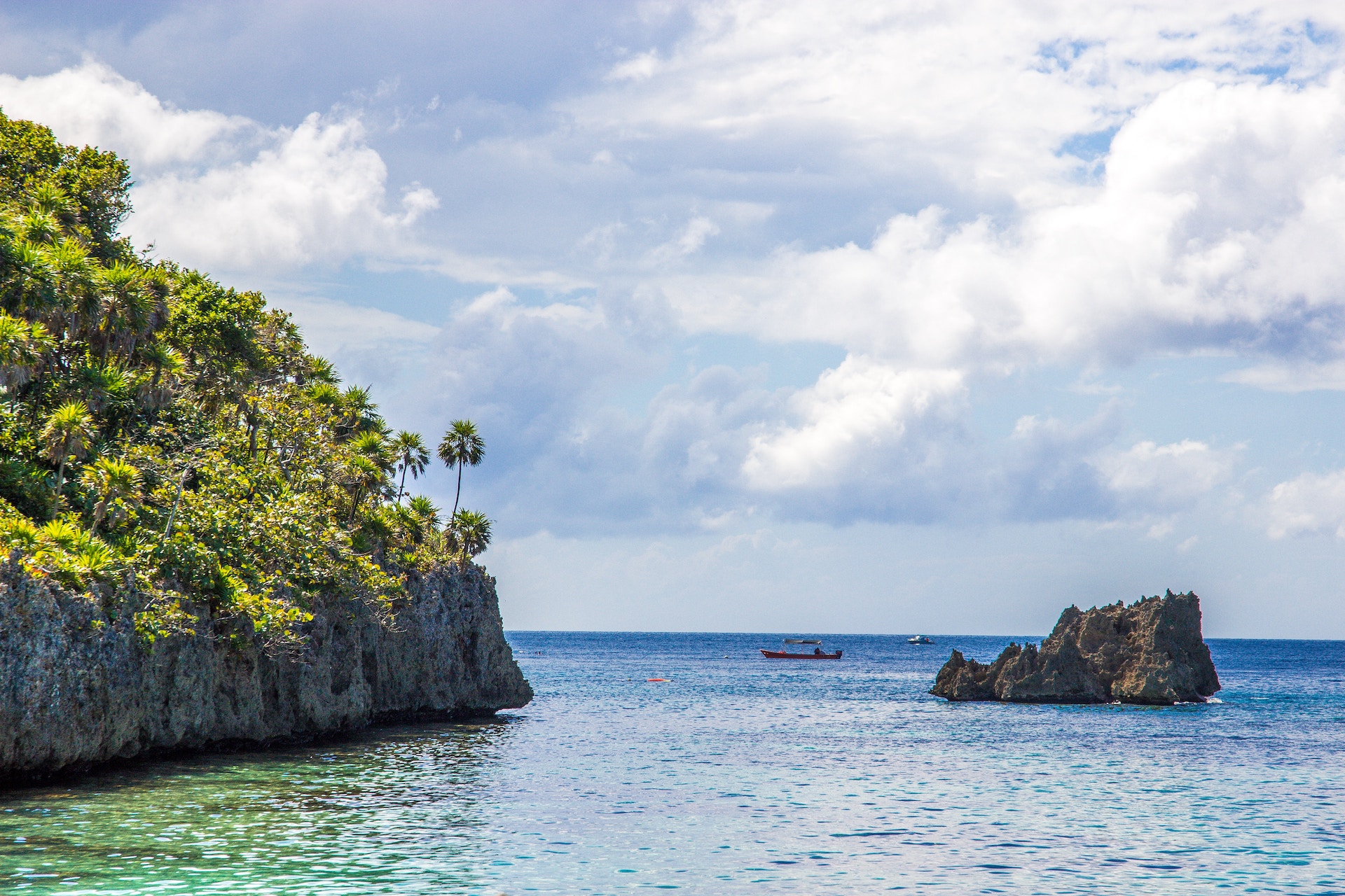 A boat and some rock formations in the waters of Roatán.