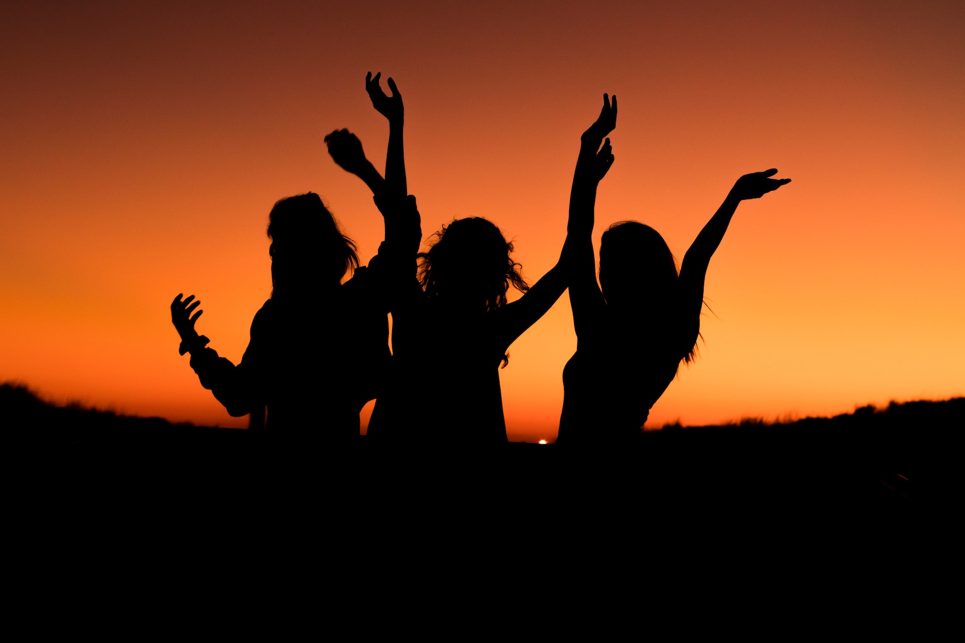 Silhouette of three women with hands on the air