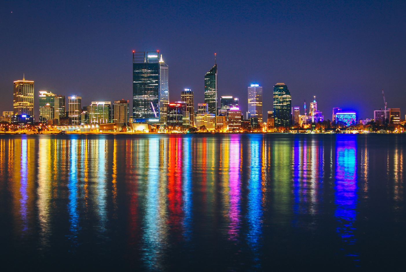 the skyline of Perth, Western Australia, at night, with the lights reflected in the water