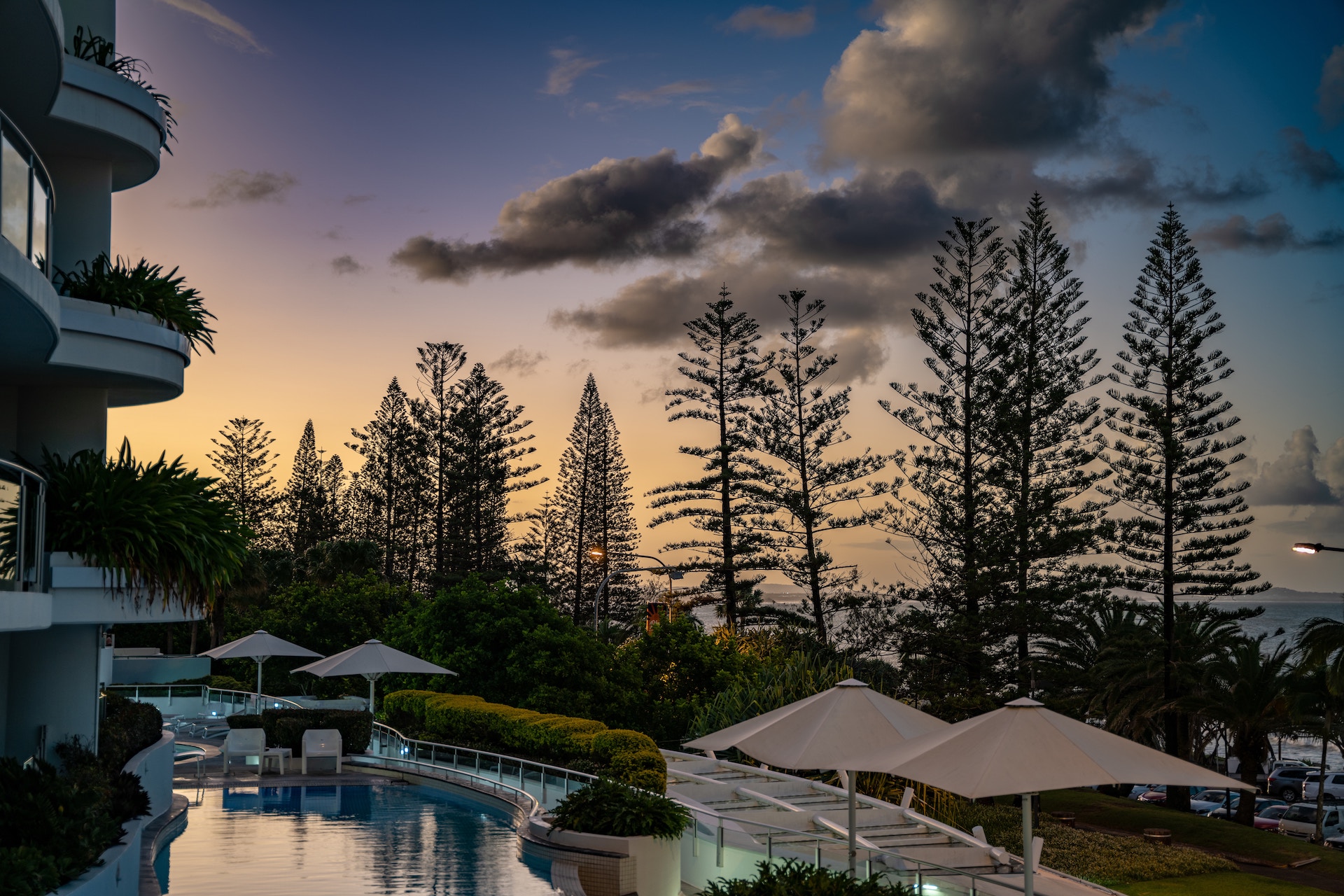 A pool beside umbrella cottages surrounded by trees at a resort on the Sunshine Coast