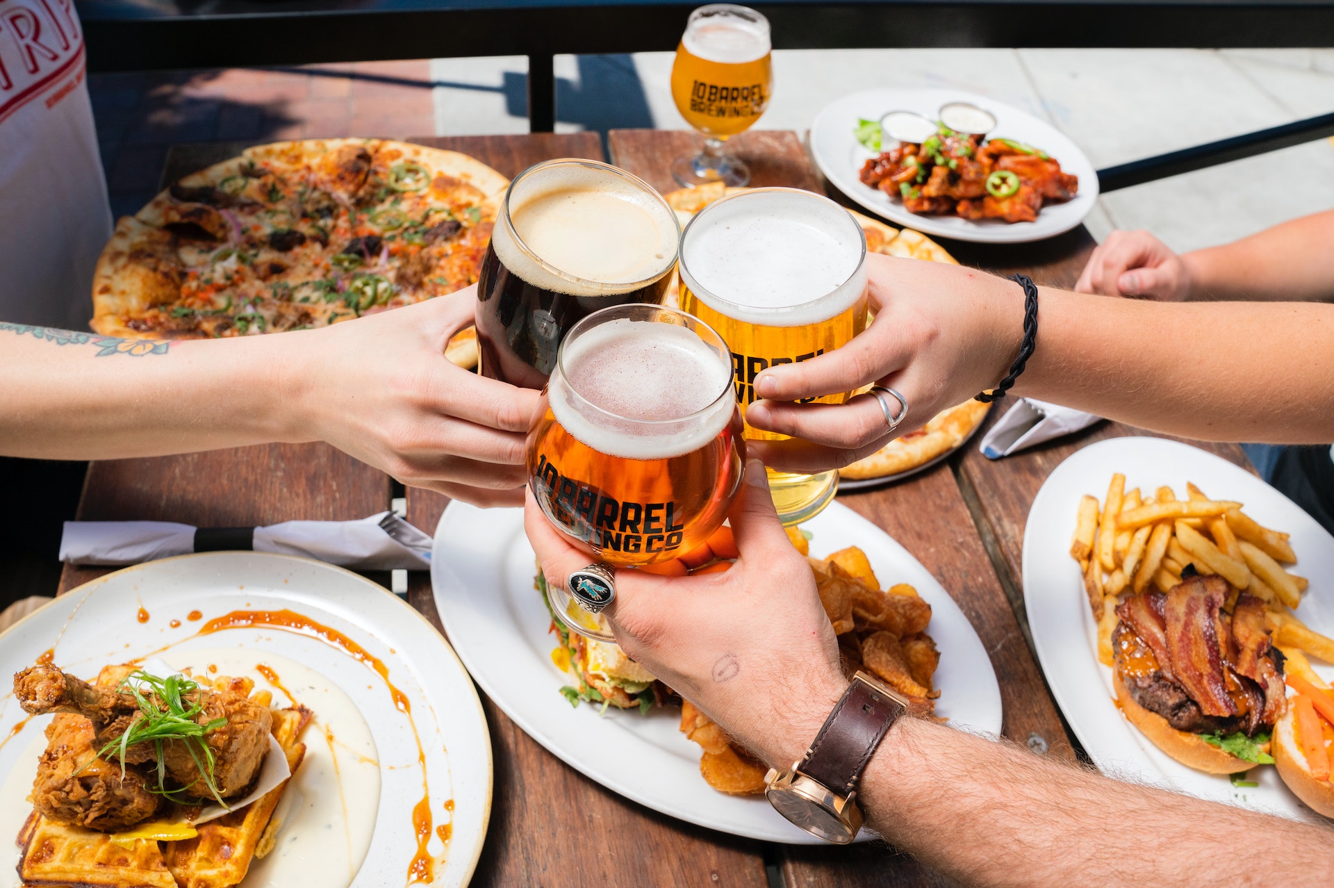 Hands of three people enjoying food and beer