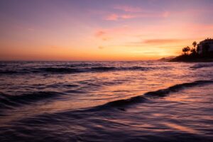 Beach waves under the gradient sunset skies in Marbella